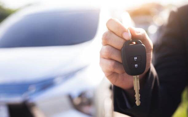 Asian man hands modern car keys ready for rent - transport concept with used car sale and trade - warm filtered image with artificial sunlight - focus on handcuffs